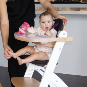 Baby in high chair at home, holding pink sippy cup, Babyhood GCC product