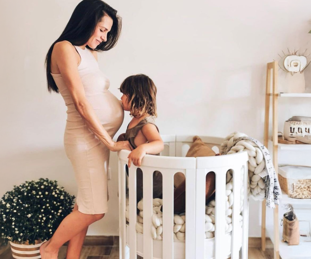 Pregnant woman with child in a modern nursery next to a round crib, Babyhood GCC