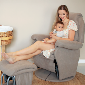 Mother sitting on grey nursing chair with baby, Babyhood GCC nursery setting