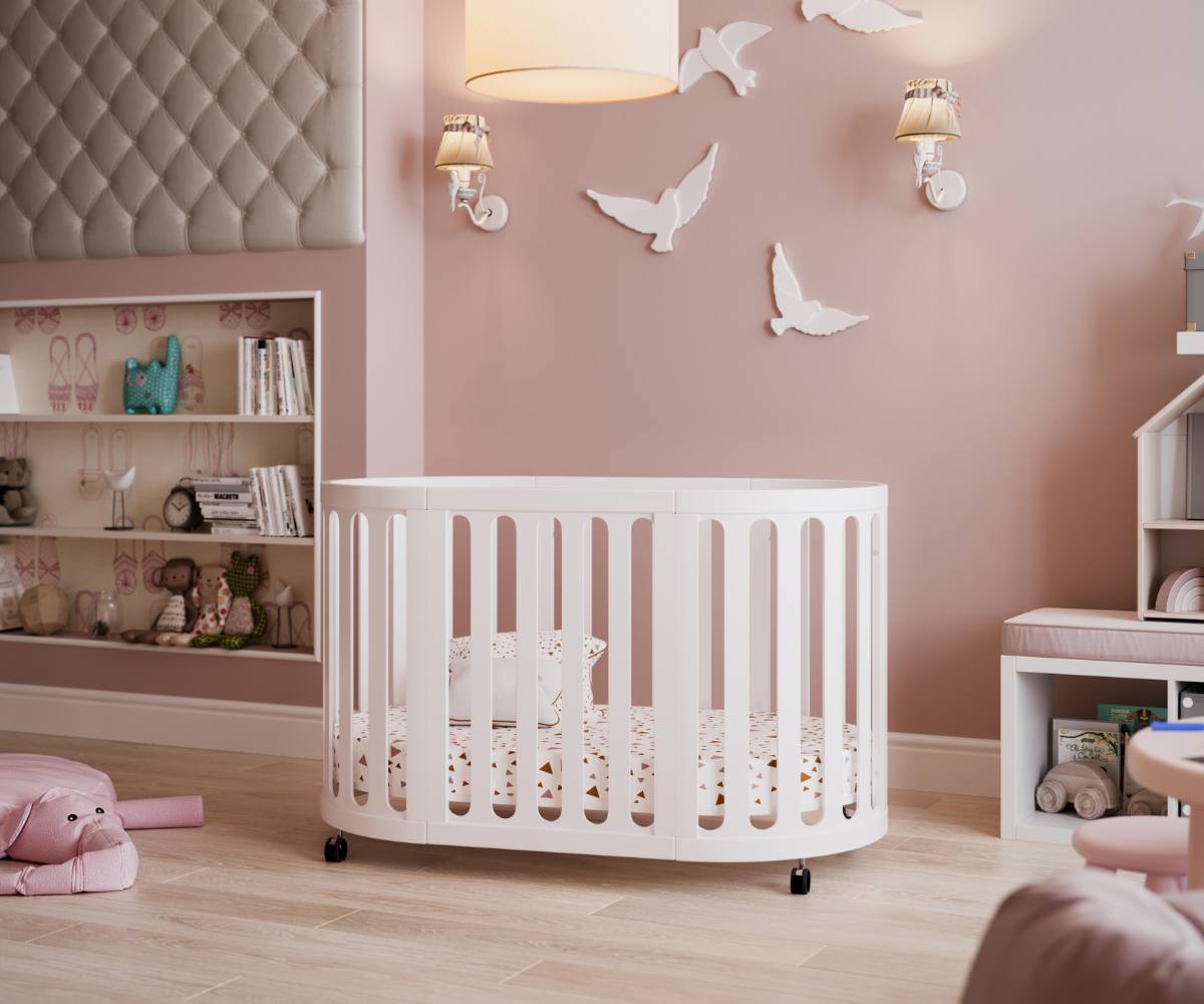 Modern white oval baby crib in pink nursery with soft toys and wall decor, Babyhood GCC