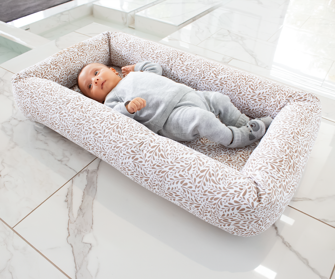 Baby lying in a patterned baby nest on marble floor, Babyhood GCC product