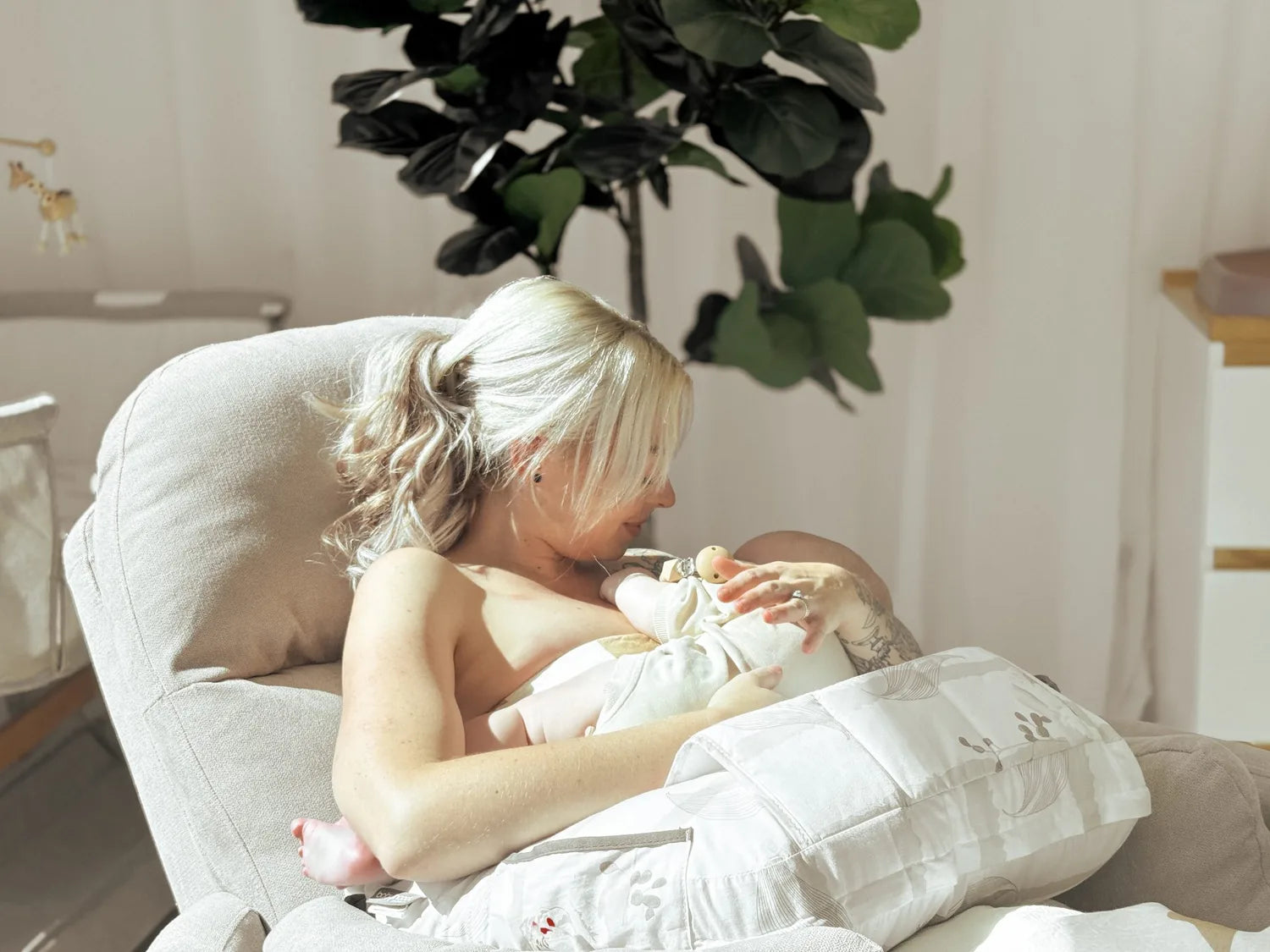A parent feeding their baby in the Firenza Latte glider chair